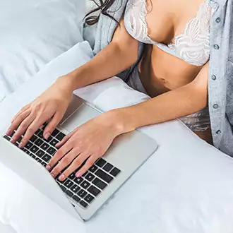 mergina su liemenėle lovoje prie kompiuterio