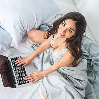 mergina apsirengusi seksualiais apatiniais lovoje su kompiuteriu
