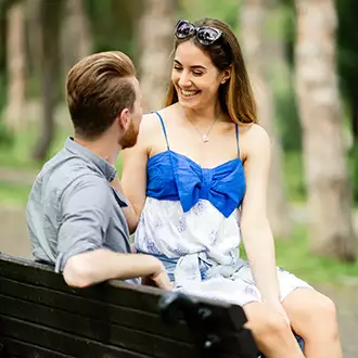 mergina sėdi vaikinui ant kelių parke