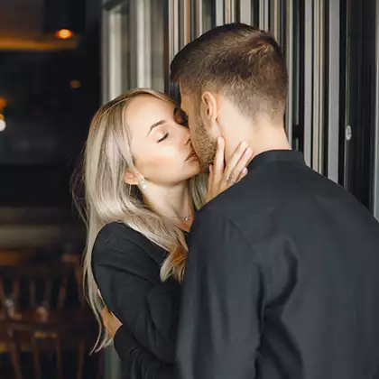 vaikinas bučiuoja merginą restorane